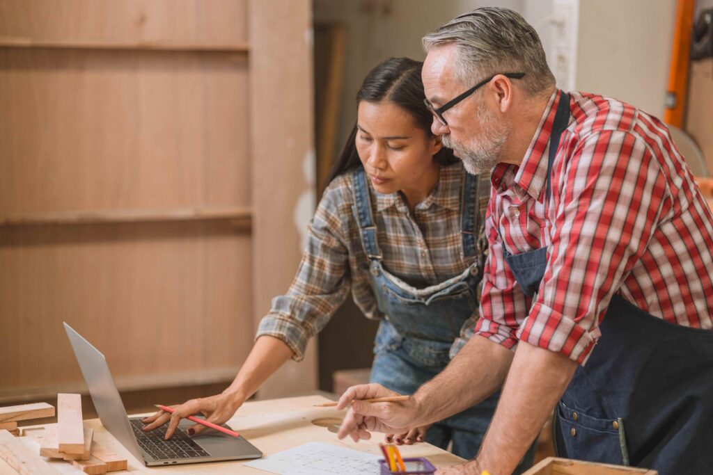Zwei Handwerker schauen gemeinsam auf einen Laptop – Webseite für Handwerksbetriebe erstellen lassen